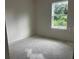 Simple bedroom featuring a large window, light-colored walls, and unfinished floors at 1445 General Mac Arthur Ave, Daytona Beach, FL 32114