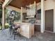 Outdoor kitchen with stone counter, stainless grill, and bar seating with lake views at 1911 Lake Markham Preserve Trl, Sanford, FL 32771