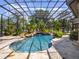 Inviting screened-in pool with lush landscaping and a tranquil waterfall feature at 1911 Lake Markham Preserve Trl, Sanford, FL 32771