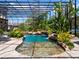 Relaxing outdoor pool area enclosed with a screen, featuring a waterfall and lush tropical plants at 1911 Lake Markham Preserve Trl, Sanford, FL 32771