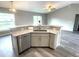 Kitchen island with sink and stainless dishwasher offers granite countertops and is open to the living area with wood flooring at 2 Fisher Lane Way, Ocklawaha, FL 32179