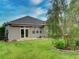 Well-maintained backyard with lush green grass, landscaped garden beds, and a covered patio at 251 Silver Maple Rd, Groveland, FL 34736