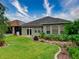 Well-maintained backyard with lush green grass, landscaped garden beds, and a covered patio at 251 Silver Maple Rd, Groveland, FL 34736