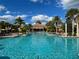 Beautiful view of a large community pool lined with palm trees and lounge chairs under a sunny, partly cloudy sky at 251 Silver Maple Rd, Groveland, FL 34736