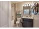 Well-lit bathroom features a shower-tub combo, vanity with storage, and decorative wall shelves at 2767 San Marco Way, Winter Haven, FL 33884
