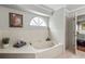 This bathroom has a large bathtub, a small frosted window, and white walls at 4436 Yachtmans Ct, Orlando, FL 32812