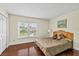 Comfortable bedroom featuring hardwood floors, a serene window view, and warm lighting at 4436 Yachtmans Ct, Orlando, FL 32812