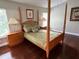 This bedroom features a four-post bed, hardwood floors, two side tables, and a window with blinds at 4436 Yachtmans Ct, Orlando, FL 32812