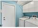 Bright laundry room with a blue wall featuring modern appliances and convenient overhead storage at 4436 Yachtmans Ct, Orlando, FL 32812