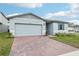 New home exterior featuring a brick driveway, garage and manicured lawn at 1489 Sea Glass Rd, Haines City, FL 33844