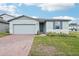 Charming single-story home featuring a well-manicured lawn, brick driveway, and a light blue exterior at 1489 Sea Glass Rd, Haines City, FL 33844