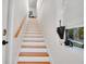 Staircase featuring white risers, hardwood treads, and a sunny window view of the backyard at 809 E Ridgewood St, Orlando, FL 32803
