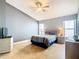 Spacious bedroom with a ceiling fan, windows and a comfortable bed with stylish striped bedding at 215 Riggs Cir, Davenport, FL 33897