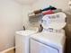 Efficient laundry room with a side-by-side washer and dryer, and storage shelves at 215 Riggs Cir, Davenport, FL 33897