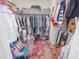 Well-organized walk-in closet featuring ample storage shelves, clothing racks, and a pink patterned rug at 745 Asturias Rd, Davenport, FL 33837