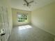 Bright bedroom with light tile flooring, ceiling fan, and a large window offering views of the outdoors at 5156 City St # 118, Orlando, FL 32839