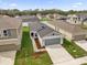 Aerial view of a one story gray home with a two car garage and green lawn at 8620 Caribbean Pine Way, Lakeland, FL 33809