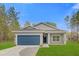 Charming single Gathering home boasts a blue garage door, green lawn, and freshly painted exterior at 95 Malauka Place Trak, Ocklawaha, FL 32179