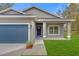 Close up of a single Gathering home showing the front door, garage door, and green lawn at 95 Malauka Place Trak, Ocklawaha, FL 32179
