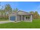 Single Gathering home boasts a blue garage door, green lawn, and freshly painted exterior at 95 Malauka Place Trak, Ocklawaha, FL 32179