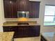 Kitchen featuring granite counters, dark cabinets, and stainless steel microwave at 2211 Rickover Pl, Winter Garden, FL 34787