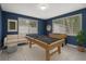 This game room includes a pool table, foosball table, couch, and two windows for natural light at 6003 Village Cir # Ge, Orlando, FL 32822
