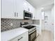 Modern kitchen with stainless steel appliances, white cabinets, quartz countertops, and stylish backsplash at 3480 Fairway Ln, Orlando, FL 32804