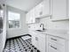 Laundry room featuring white cabinets, black hardware, unique black and white floors, and stainless steel sink at 3480 Fairway Ln, Orlando, FL 32804