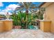 Charming balcony featuring stone tiles, decorative railing, and stone pineapple ornamentation overlooking beautiful landscaped garden and pool area at 1400 Alabama Dr, Winter Park, FL 32789