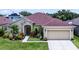 Charming single Gathering home features a well-manicured lawn, tropical landscaping, and attached two car garage at 17843 Golden Leaf Ln, Orlando, FL 32820
