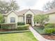 Home featuring an attractive entrance with a double door, brick walkway, meticulously maintained landscaping, and manicured lawn at 11602 Graces Way, Clermont, FL 34711