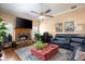Cozy living room with a stone fireplace, hardwood floors, and a large ceiling fan at 11602 Graces Way, Clermont, FL 34711