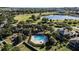 Aerial view of the community pool, jacuzzi, and surrounding green spaces with a lake in the background at 2855 Gopherwood Way, Clermont, FL 34711