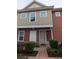 Townhome entrance with a walkway, landscaping, and a light beige and red exterior at 7532 Sunville Ave, Kissimmee, FL 34747