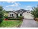 Single-story home with stone accents, landscaping, and a paved driveway at 30215 Bretton Loop, Mount Dora, FL 32757