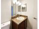 A clean bathroom features a sink with a brown vanity, lights, mirror and toilet at 4367 Thornbriar Ln # 108, Orlando, FL 32822