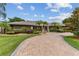 Luxury home exterior with a brick driveway, lush landscaping, and palm trees at 9227 Cypress Cove Dr, Orlando, FL 32819