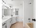 Bright, tiled bathroom with dual sinks, modern lighting, and a separate bathtub/shower area at 225 Terrace Hill Blvd # 1C, Debary, FL 32713