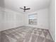 Bright bedroom with a ceiling fan, window, and closet, featuring patterned carpet at 225 Terrace Hill Blvd # 1C, Debary, FL 32713
