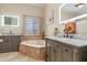 Bright bathroom featuring double vanity, soaking tub under a window, and modern fixtures at 33412 E Lake Joanna Dr, Eustis, FL 32736