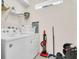 Well-lit laundry room with modern washer and dryer, shelving, and cleaning supplies at 1870 Summer Dr, Davenport, FL 33897