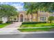 Stately two-story home featuring a symmetrical design, arched windows, and a brick driveway, nestled among mature trees at 334 Chadwick Dr, Davenport, FL 33837