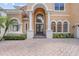 Welcoming front entrance showcasing an arched doorway, elegant pillars, and a brick driveway for a touch of classic charm at 334 Chadwick Dr, Davenport, FL 33837