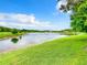 Scenic view of a pond surrounded by lush greenery and a blue sky with clouds at 2543 Old Kent Cir, Kissimmee, FL 34758