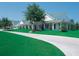 White single story building with a green roof surrounded by green grass and trees at 2608 Kinsale Ln, Ormond Beach, FL 32174