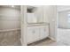 Bathroom with a double sink vanity featuring speckled countertops, leading to a walk-in closet and bedroom at 1709 Forest Run Ln, Auburndale, FL 33823