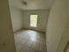 A simple bedroom featuring neutral tile flooring and a window for natural light at 821 Savona Pl, Kissimmee, FL 34758