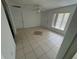 Open living room features neutral tile flooring, ceiling fan, two windows, and two doors at 821 Savona Pl, Kissimmee, FL 34758
