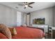 Comfortable bedroom featuring a ceiling fan and a large TV with a nature scene displayed at 8300 Ludington Cir, Orlando, FL 32836