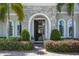 Elegant front entrance with stone archway, arched windows, and lush landscaping at 8300 Ludington Cir, Orlando, FL 32836
